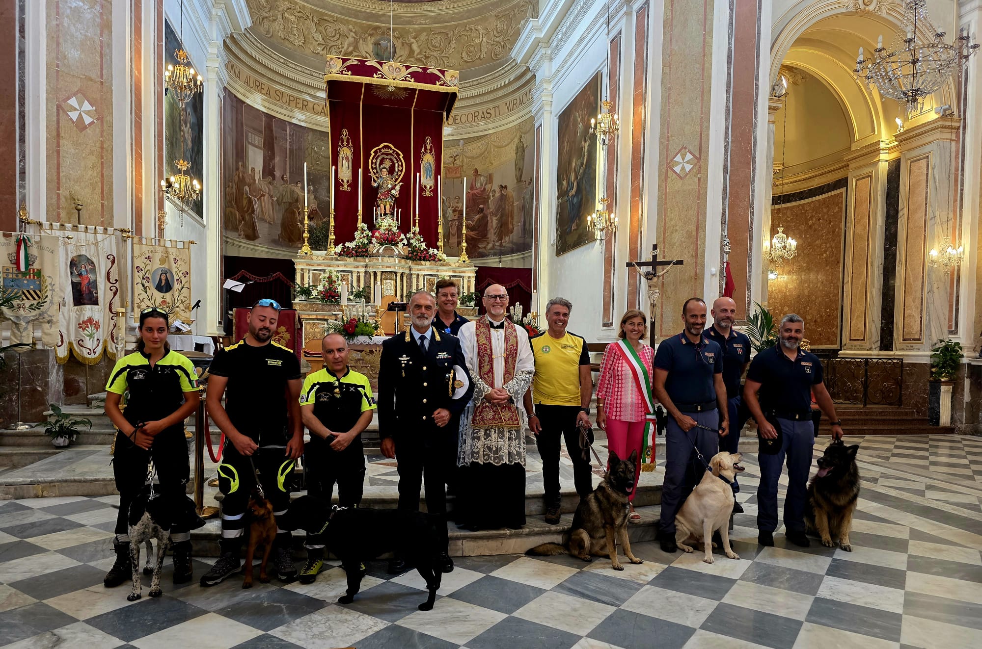 Foto di gruppo all'interno della chiesa a Mascalucia con le unità cinofile, le autorità locali, le forze dell'ordine e il parroco davanti all'altare. Scatto di Mari Longo.