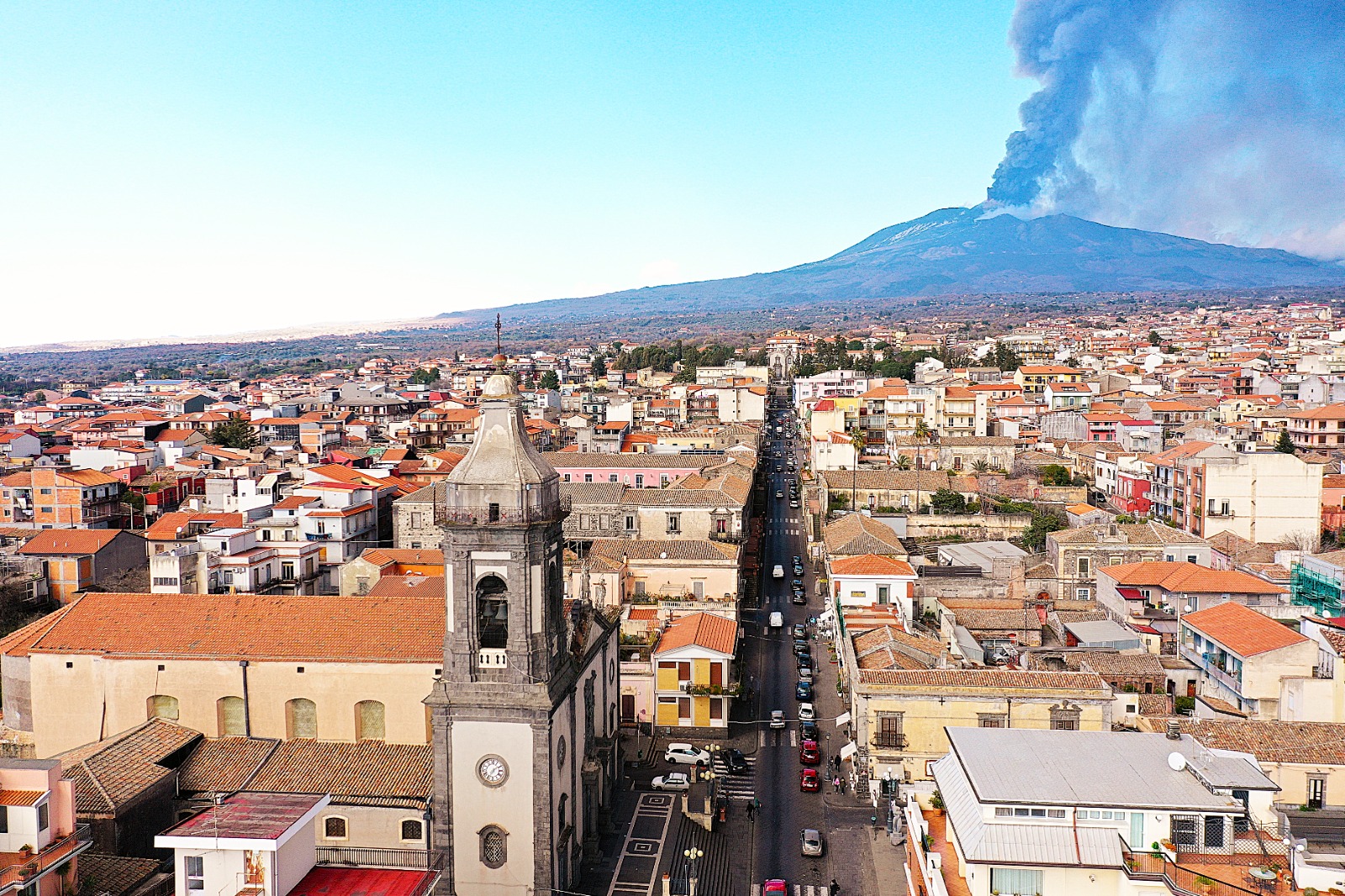Veduta aerea di Belpasso con la Chiesa Madre e l'Etna in eruzione sullo sfondo, foto di Antonello Signorello.